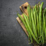 Green beans on black slate background.