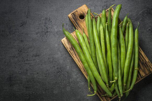 Green beans on black slate background.