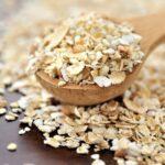 Oat flakes on a wooden spoon close-up