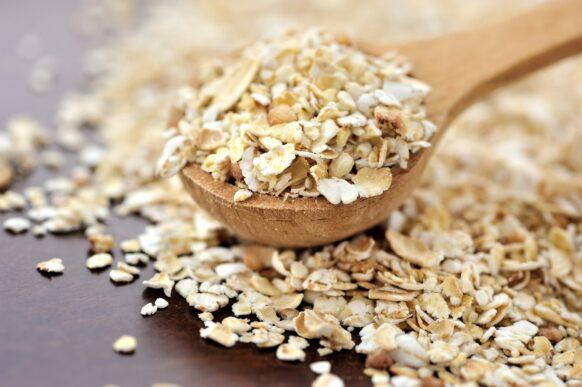 Oat flakes on a wooden spoon close-up