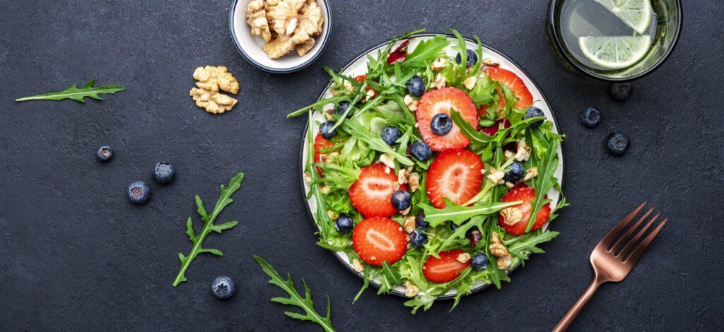 Strawberry and herbs healthy salad with arugula, blueberries and walnuts