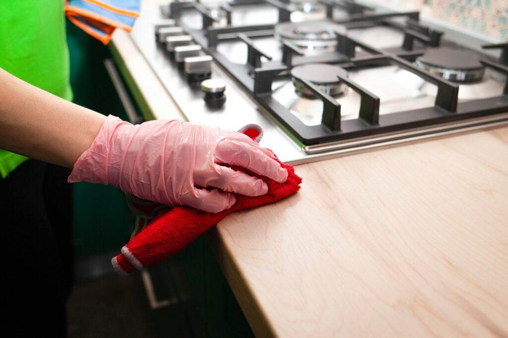 woman in gloves wipes furniture in the kitchen