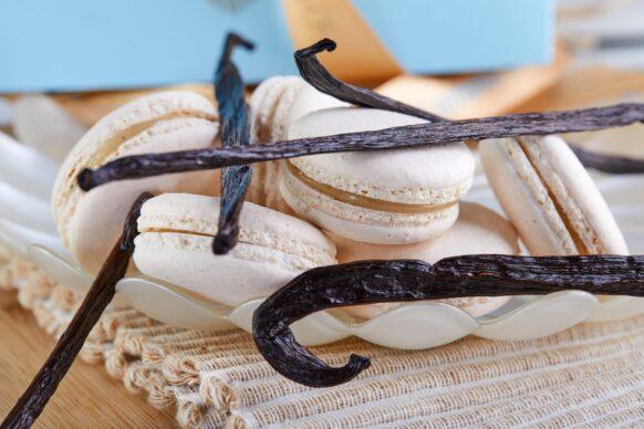 A stack of macarons and vanilla beans on a plate, a happy event