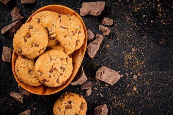 Wooden plate with cookies and pieces of milk chocolate.